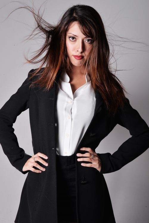 Free Stylish and confident woman in business attire posing with dynamic hair movement in a studio setting. Stock Photo