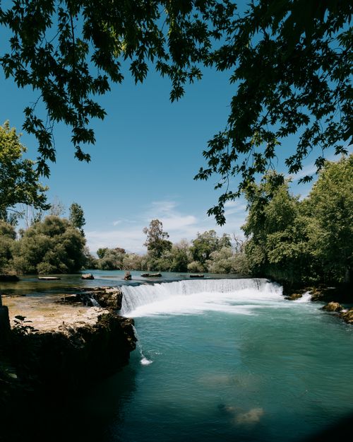 Free Beautiful waterfall in Manavgat, Türkiye, surrounded by lush greenery under a clear blue sky. Stock Photo