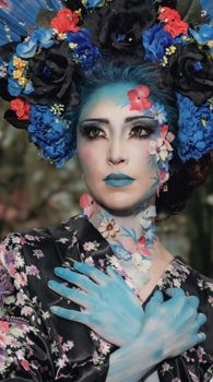 A vibrant portrait of a woman in floral fantasy makeup, with a kimono and colorful headdress.