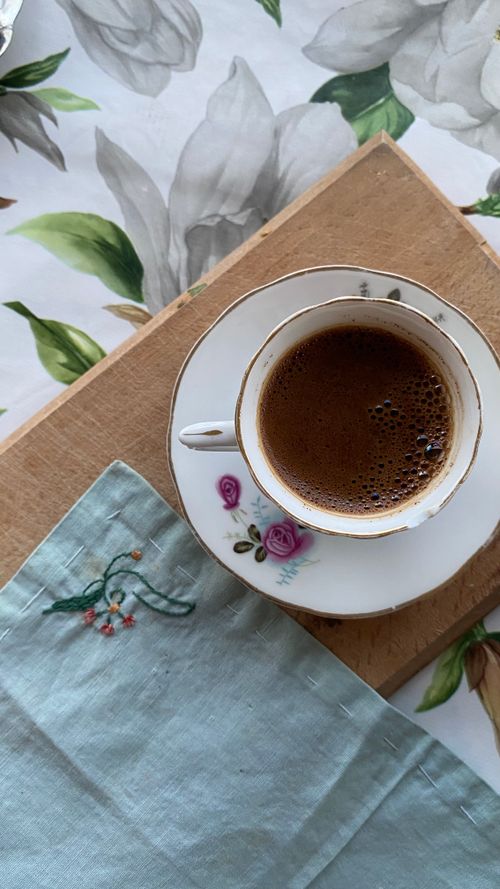 Free A rustic scene of a hot coffee in a floral saucer on a wooden tray with a decorative napkin. Stock Photo