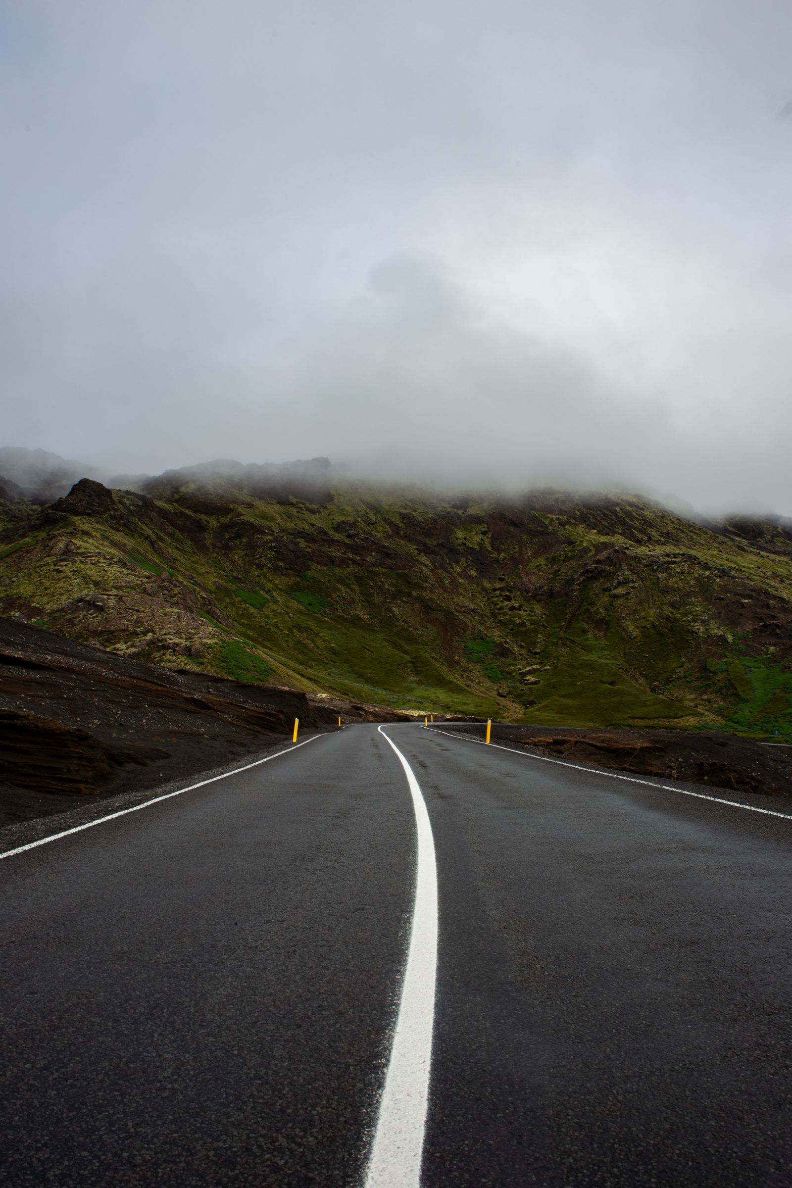 A misty Icelandic road winding through a dramatic open landscape