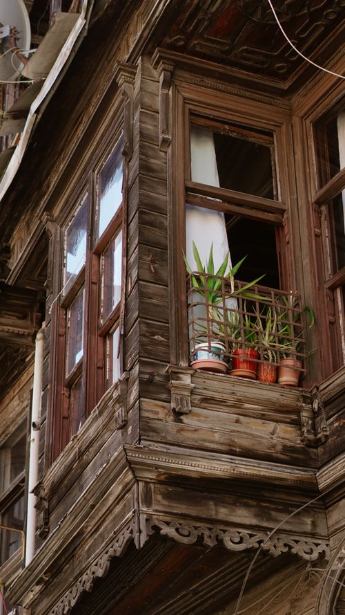 Free A rustic wooden balcony with potted plants adds charm to an antique building facade. Stock Photo