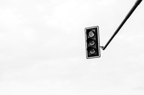 Free Black and white image of a traffic light against a cloudy sky, emphasizing urban minimalism. Stock Photo