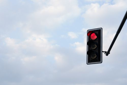 Free Red traffic light set against a bright, cloudy sky. Perfect for themes of travel, technology, and safety. Stock Photo