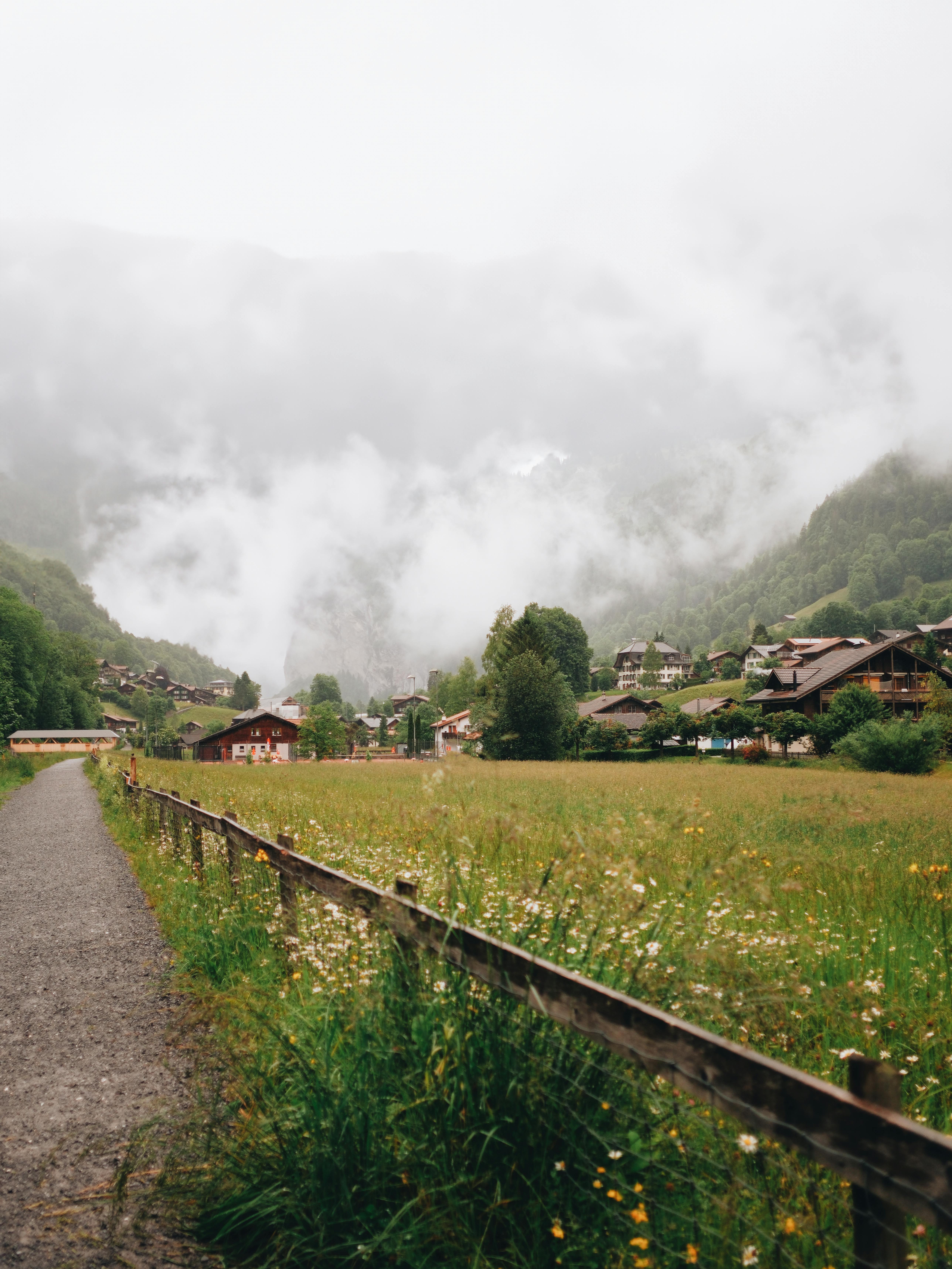 a path leading to a small village with a foggy sky