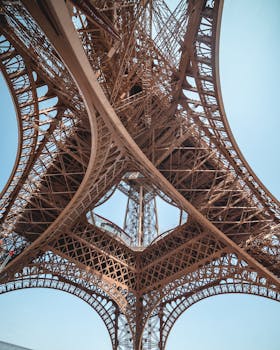 从下方观看，巴黎埃菲尔铁塔复杂的铁结构在晴朗的天空下显得格外清晰