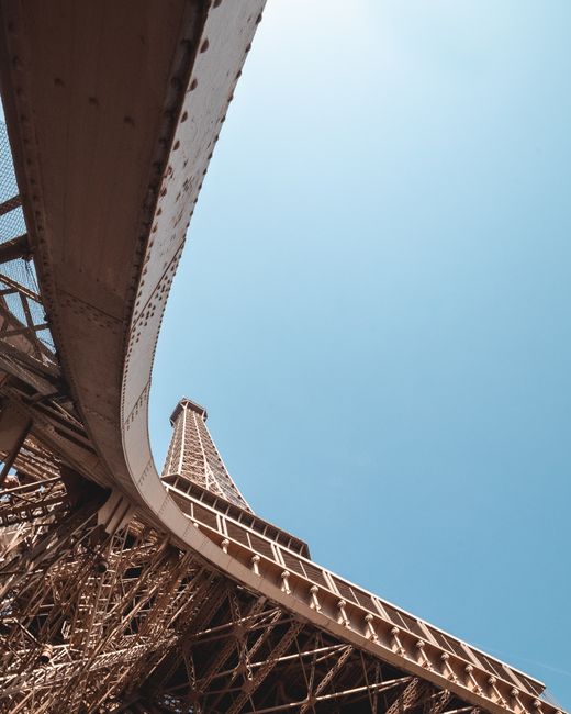 A striking low-angle view of the Eiffel Tower against a clear blue sky in Paris.
