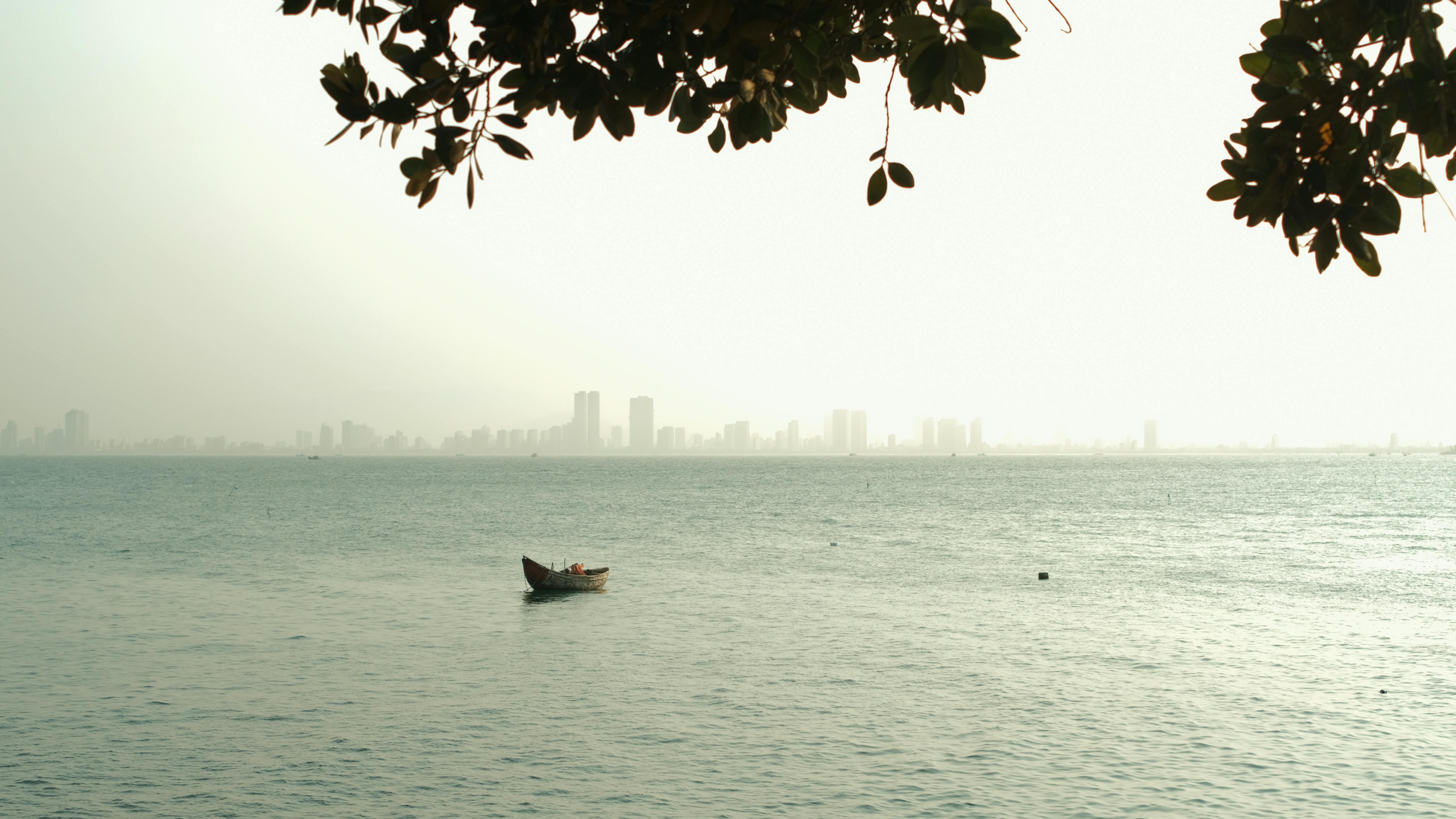 Calm scene of a lone boat against Da Nang's skyline at dusk, Vietnam.