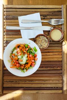 Bright and colorful salad with dressing on a rustic wooden table.
