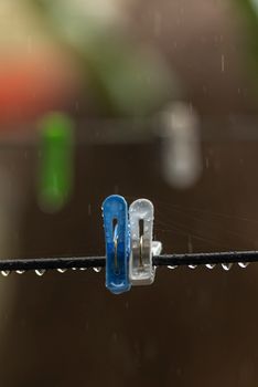 Close-up of colorful clothespins on a line with raindrops, evoking a minimalist rainy day mood.