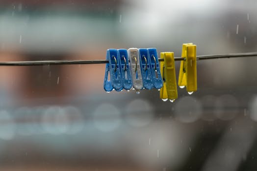 Close-up of wet plastic clothespins hanging on a line during rainfall.