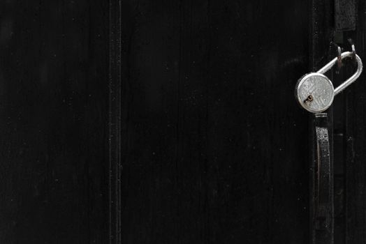 A minimalistic black gate featuring a silver padlock, emphasizing security and secrecy.
