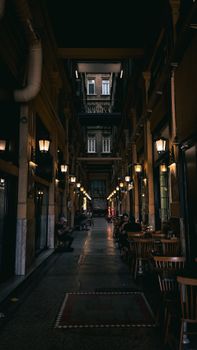 Dimly lit vintage alleyway with warm lighting, cafes, and historic building facades at night.