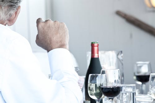 Free Man Sitting Near Wine Bottle and Glasses Stock Photo