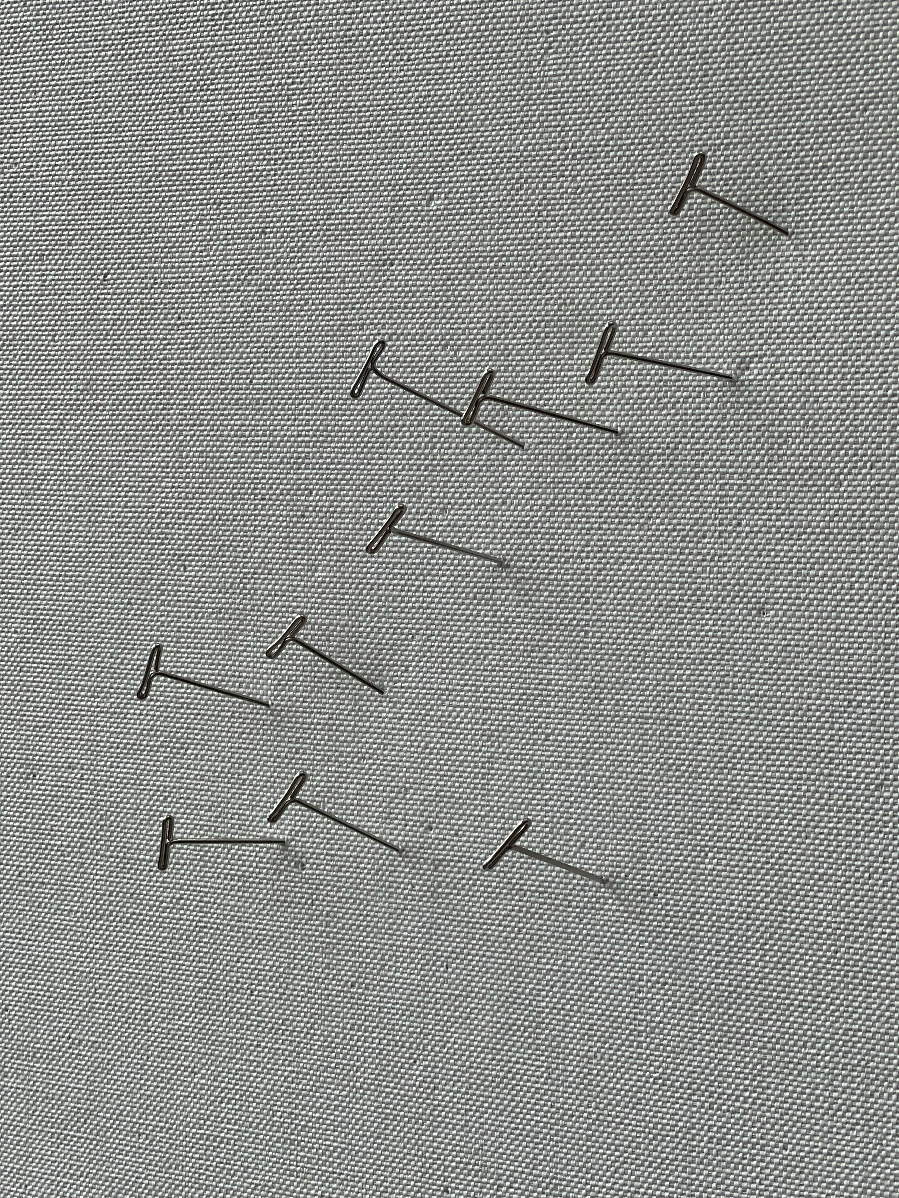 Free Abstract arrangement of T-pins on gray fabric showing texture and pattern. Stock Photo