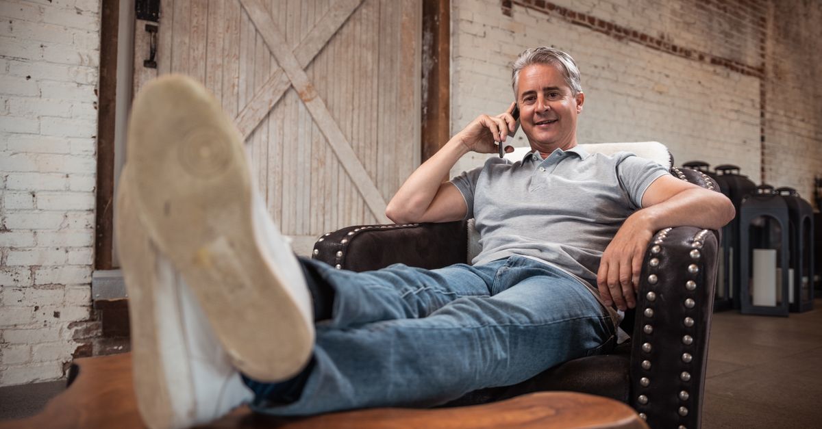 Hispanic man on phone comparing auto insurance quotes in Florida, relaxed at home