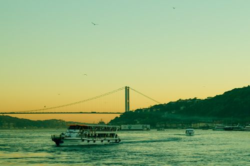 Free A serene view of the Bosphorus Bridge in Istanbul with boats at sunset. Stock Photo