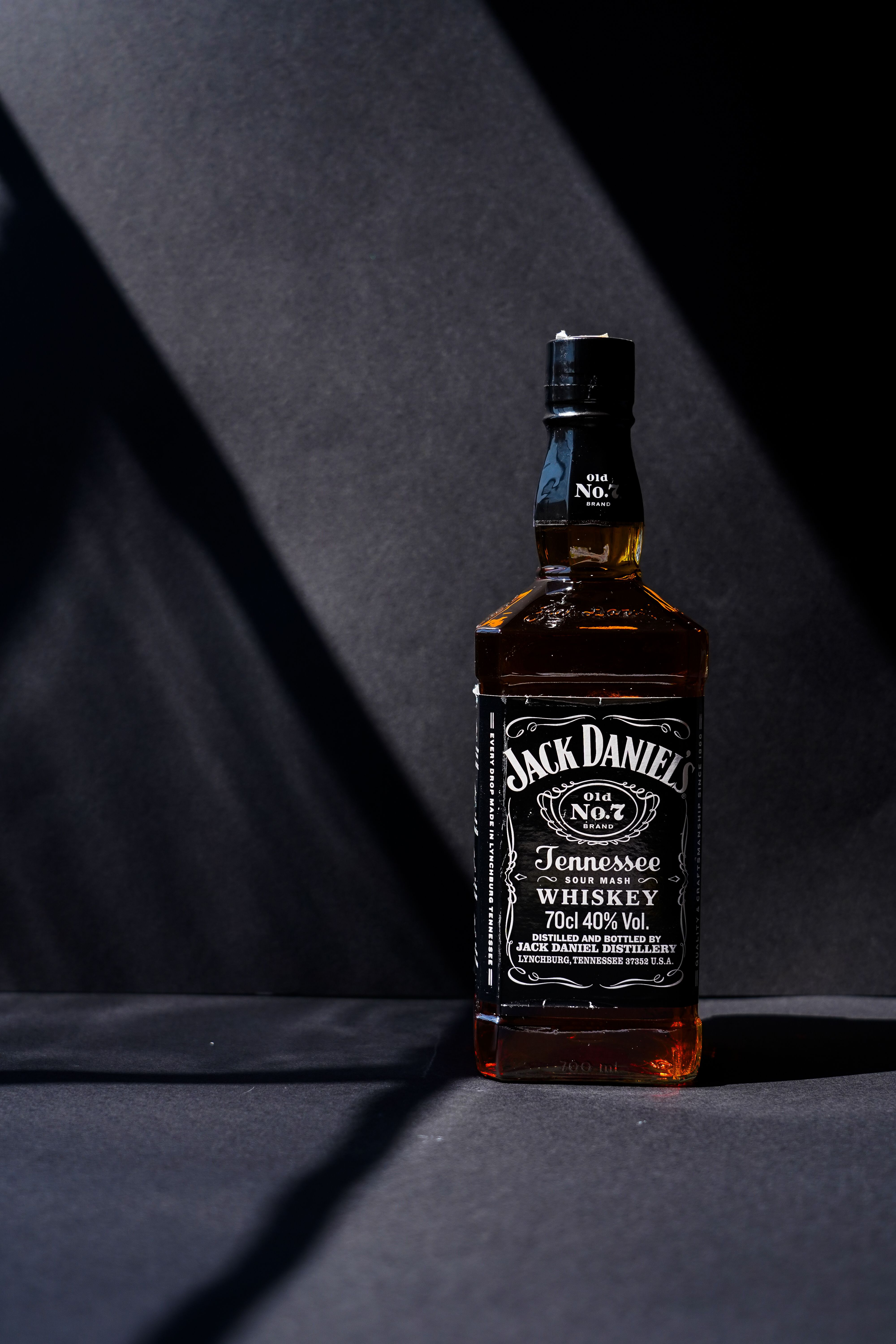 A Jack Daniel's Tennessee Whiskey bottle elegantly showcased against a dark background with dramatic lighting.