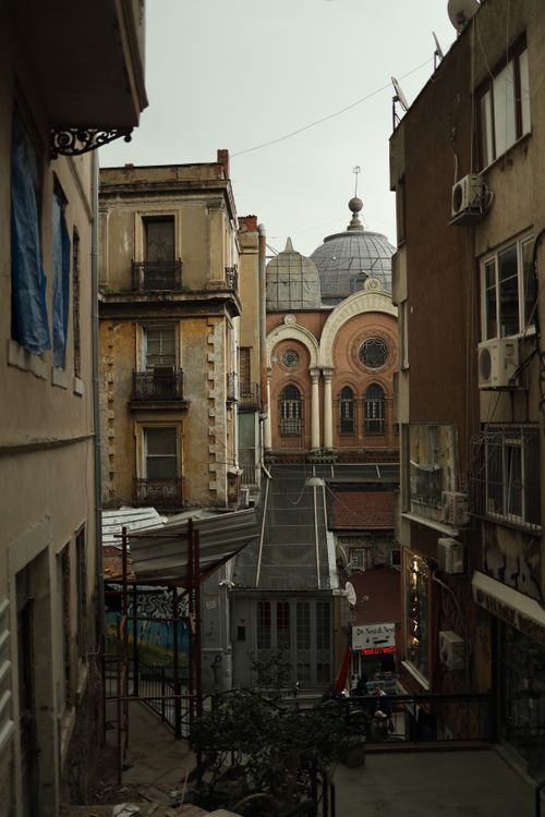 Free Narrow urban street view with aged architecture and a church at dusk, evoking old-world charm. Stock Photo