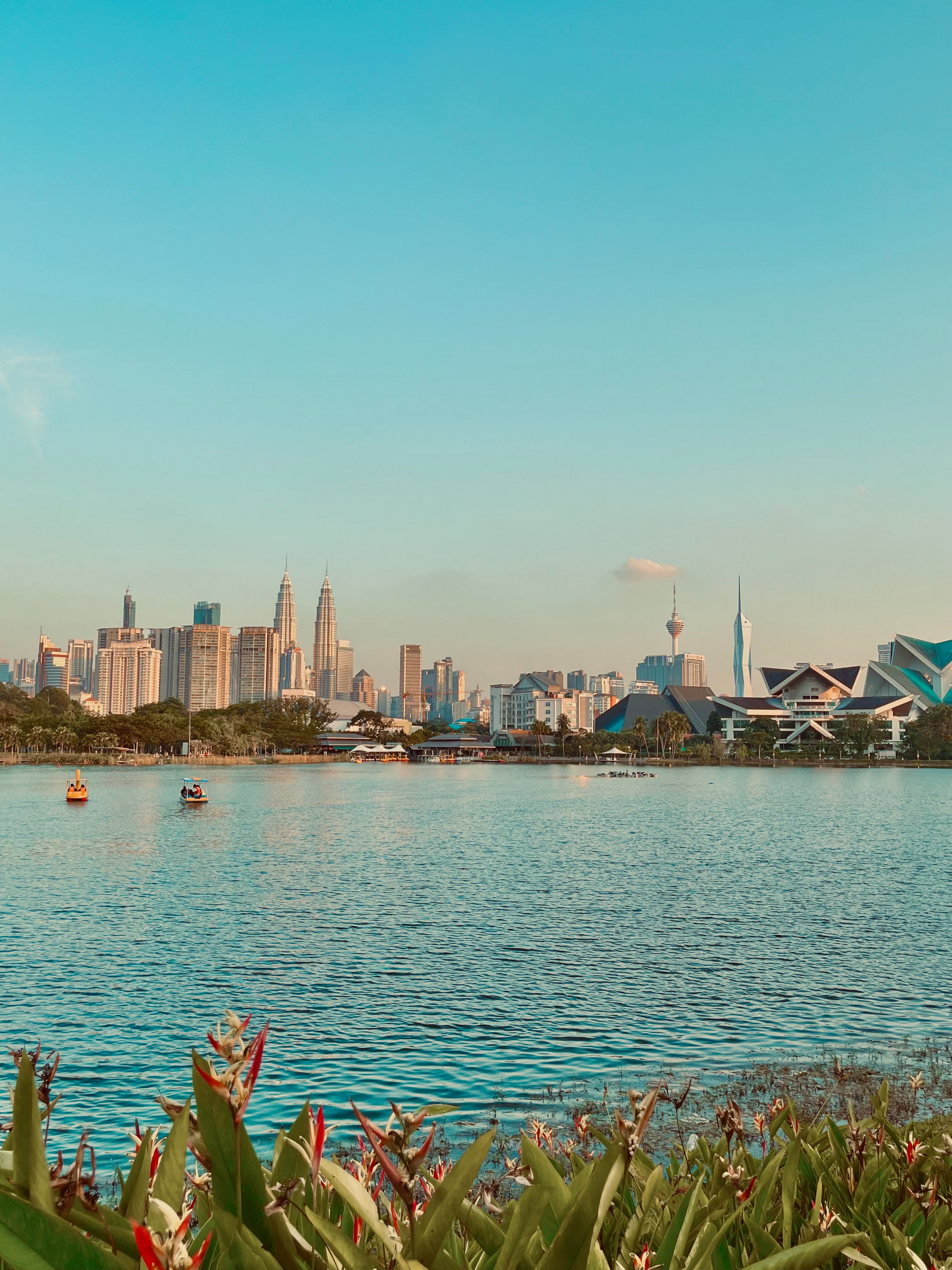 Scenic view of Kuala Lumpur's skyline across the water at sunset, highlighting iconic city landmarks.