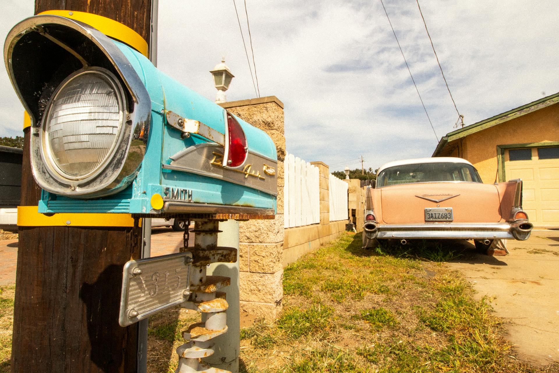 A classic vintage car parked near a retro mailbox with nostalgic vibes in a suburban setting.