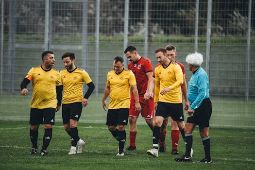 Amateur soccer players in yellow uniforms and referee on the field after a match.