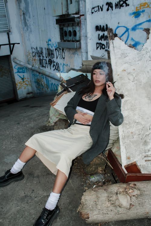 Free Young woman poses with cigarette in graffiti-covered alley, showcasing urban fashion. Stock Photo