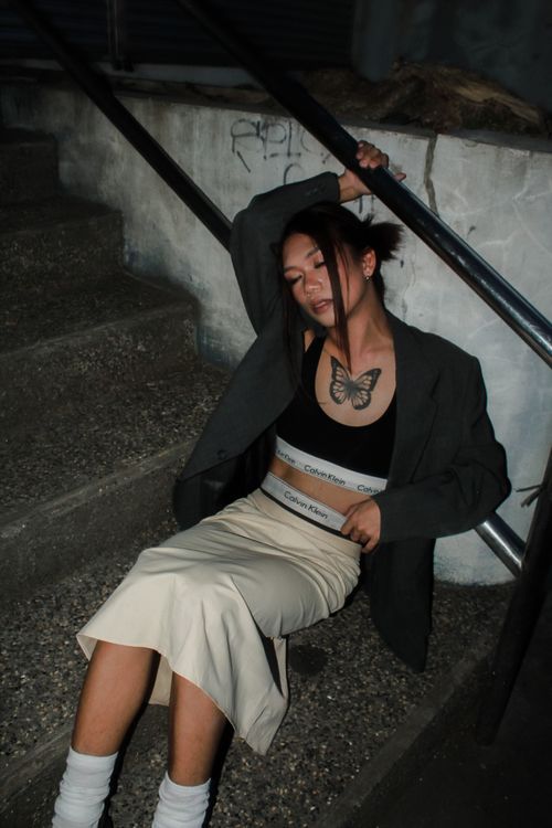 Free Fashionable woman sitting on steps in an urban setting, embodying a moody street style. Stock Photo