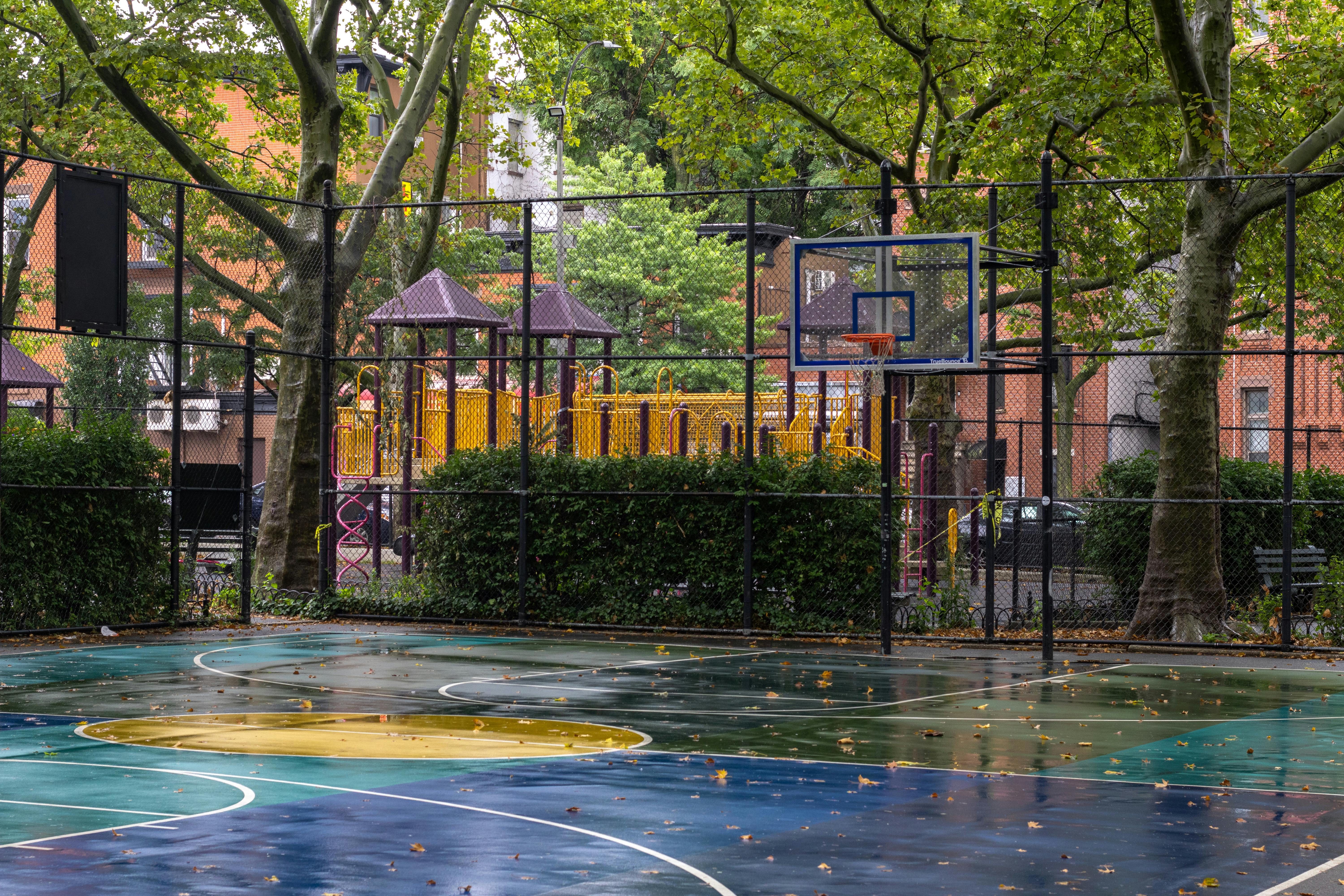 a basketball court with a playground in the background