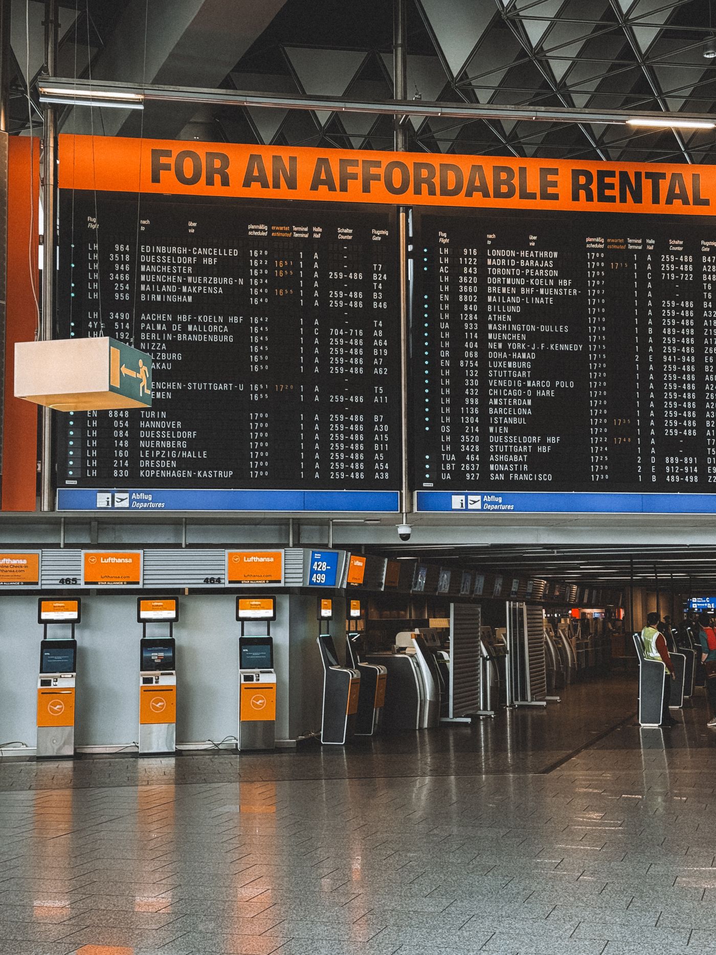 Departure hall at Frankfurt Airport with the flight information board and check-in kiosks