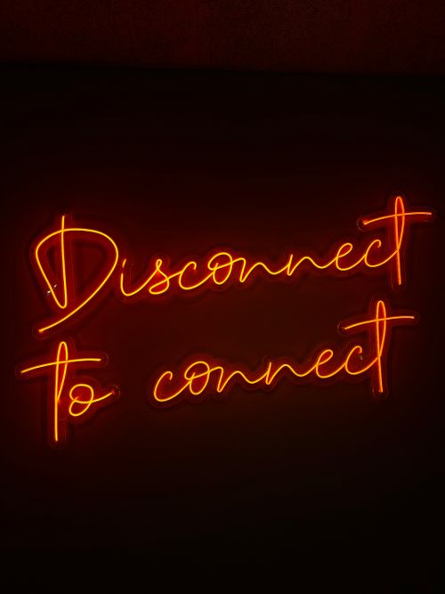 Free Eye-catching neon sign with 'Disconnect to Connect' message on dark background. Stock Photo