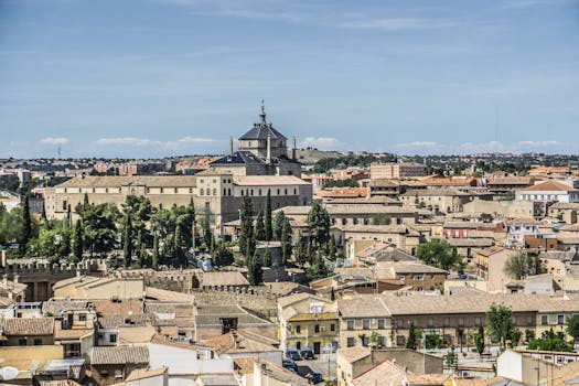Aerial view of Toledo's historic architecture and lush greenery under a clear blue sky.