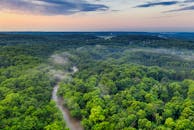 日落时分，郁郁葱葱的绿色森林、河流和薄雾共同展现了大自然的美丽