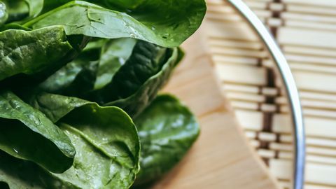 Close-up of fresh spinach leaves on a wooden cutting board, perfect for healthy cooking themes.