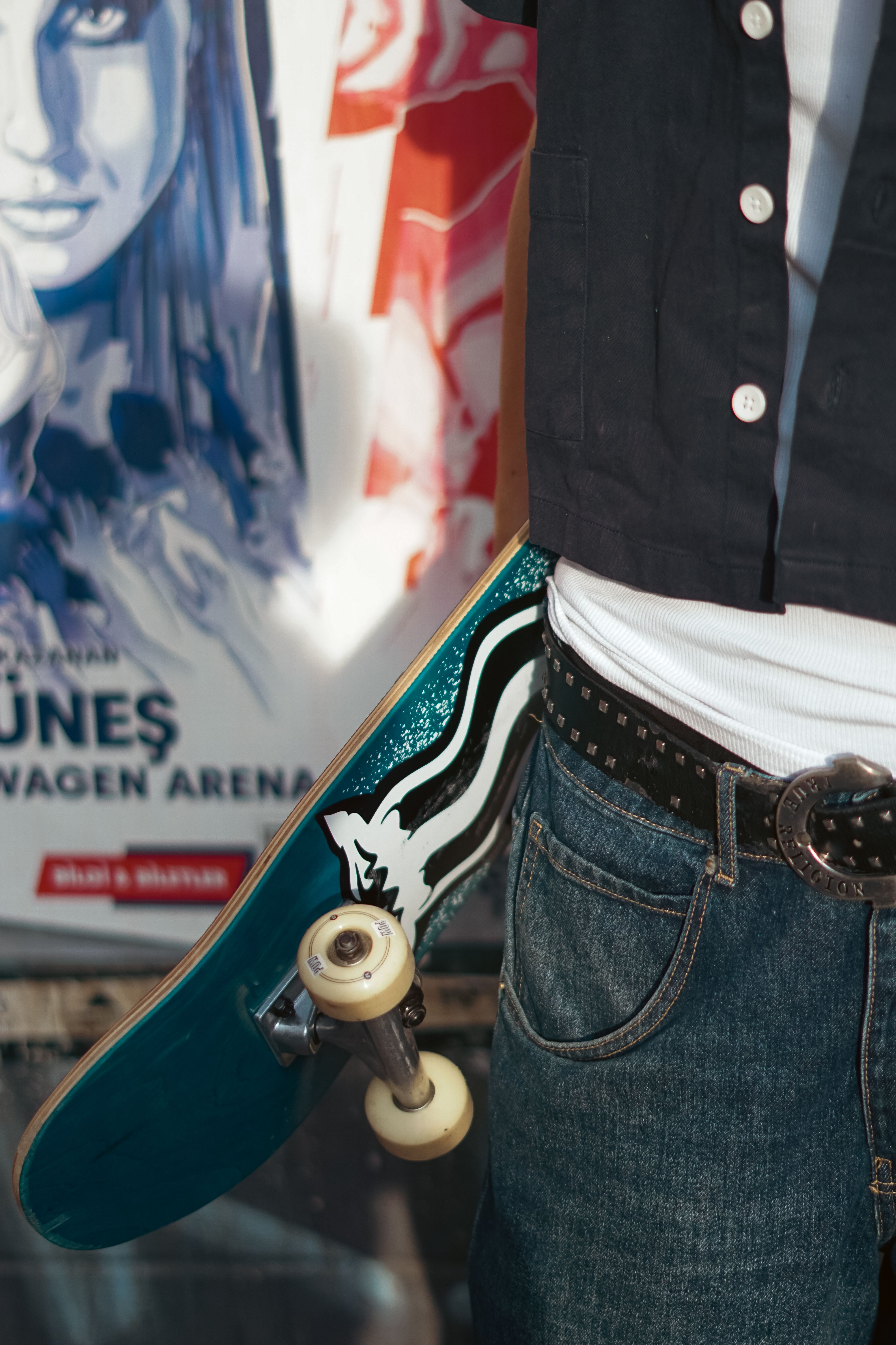 Stylish urban fashion shot of a skater holding a skateboard in a city setting.
