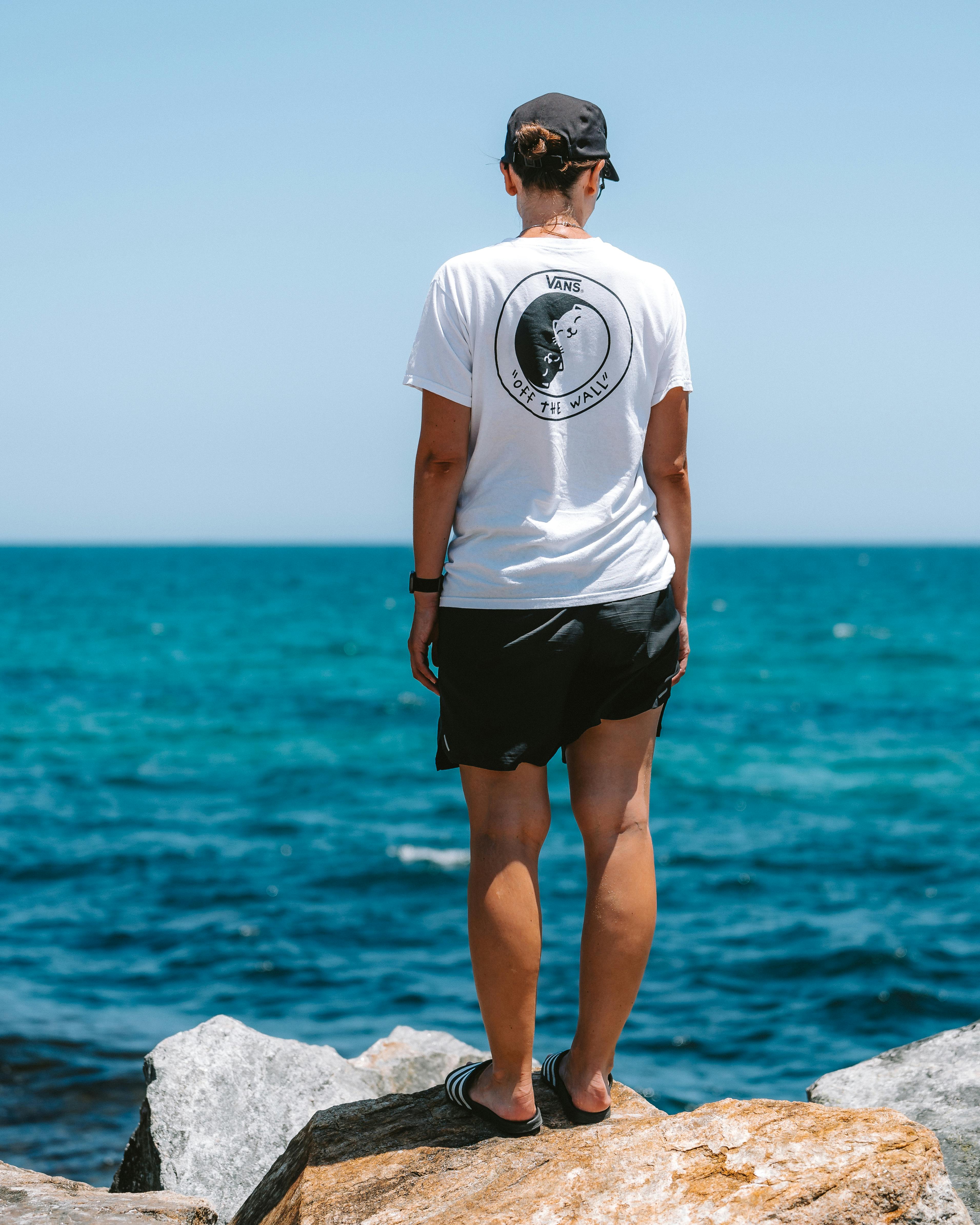 a woman standing on the rocks looking out to sea