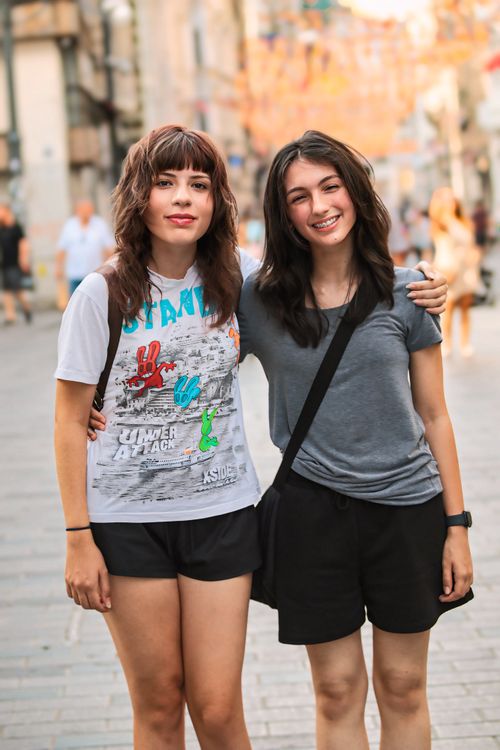 Free Two young women happily embrace on a sunny urban street, enjoying friendship and summer vibes. Stock Photo