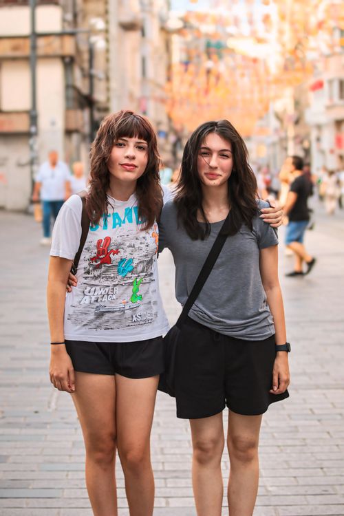 Free Two young women stand together on a vibrant city street, embracing and smiling. Stock Photo