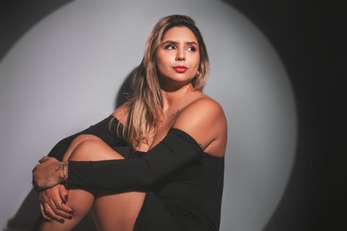 Free Fashion portrait of a young woman sitting elegantly under dramatic studio lighting. Stock Photo