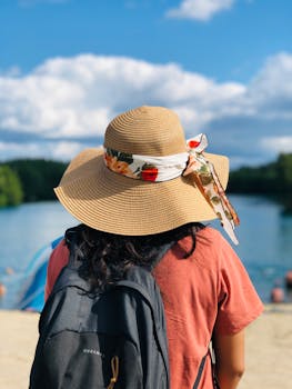 A woman enjoys a sunny summer day at the beach in Stockholm, Sweden, wearing a straw hat.