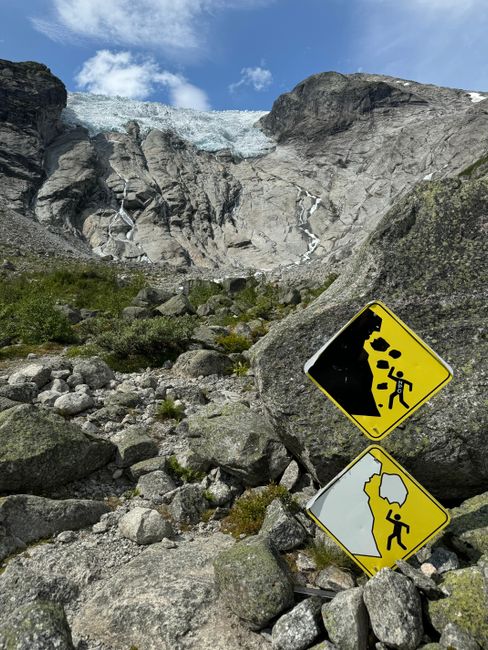 Photo by Petra Nesti Rocky mountain landscape with warning signs indicating potential rockfalls, under a clear blue sky.