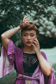 一位妆容鲜艳、戴着头巾的优雅女性，在自然光线下于户外自信地摆着姿势