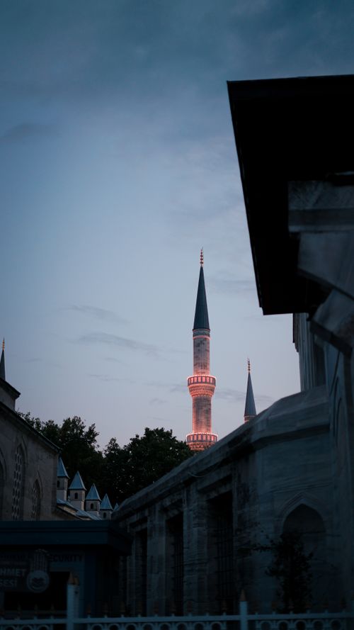 Free A mosque minaret illuminated against the evening sky, showcasing architectural beauty. Stock Photo