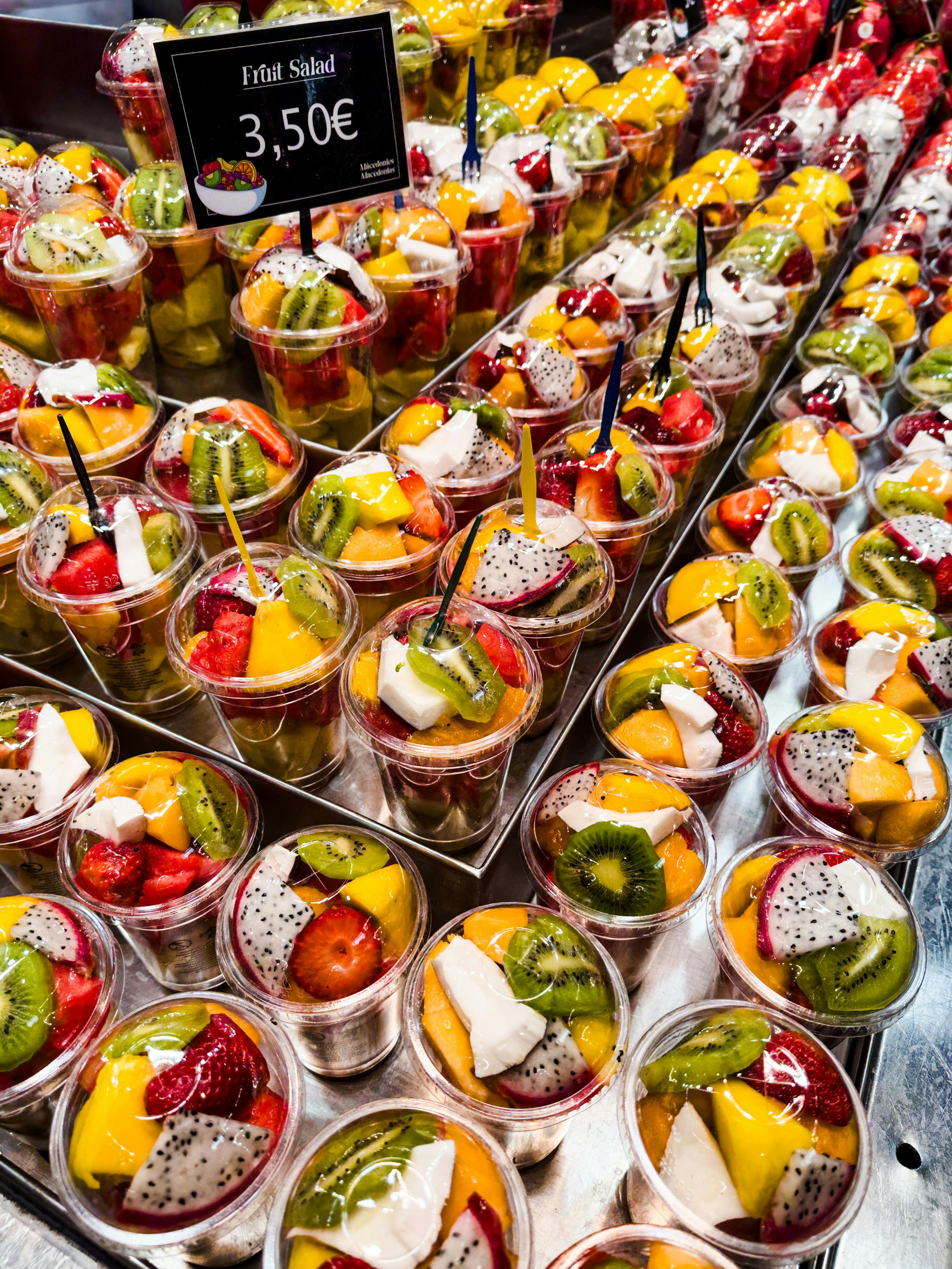 a display of fruit in cups with prices on them