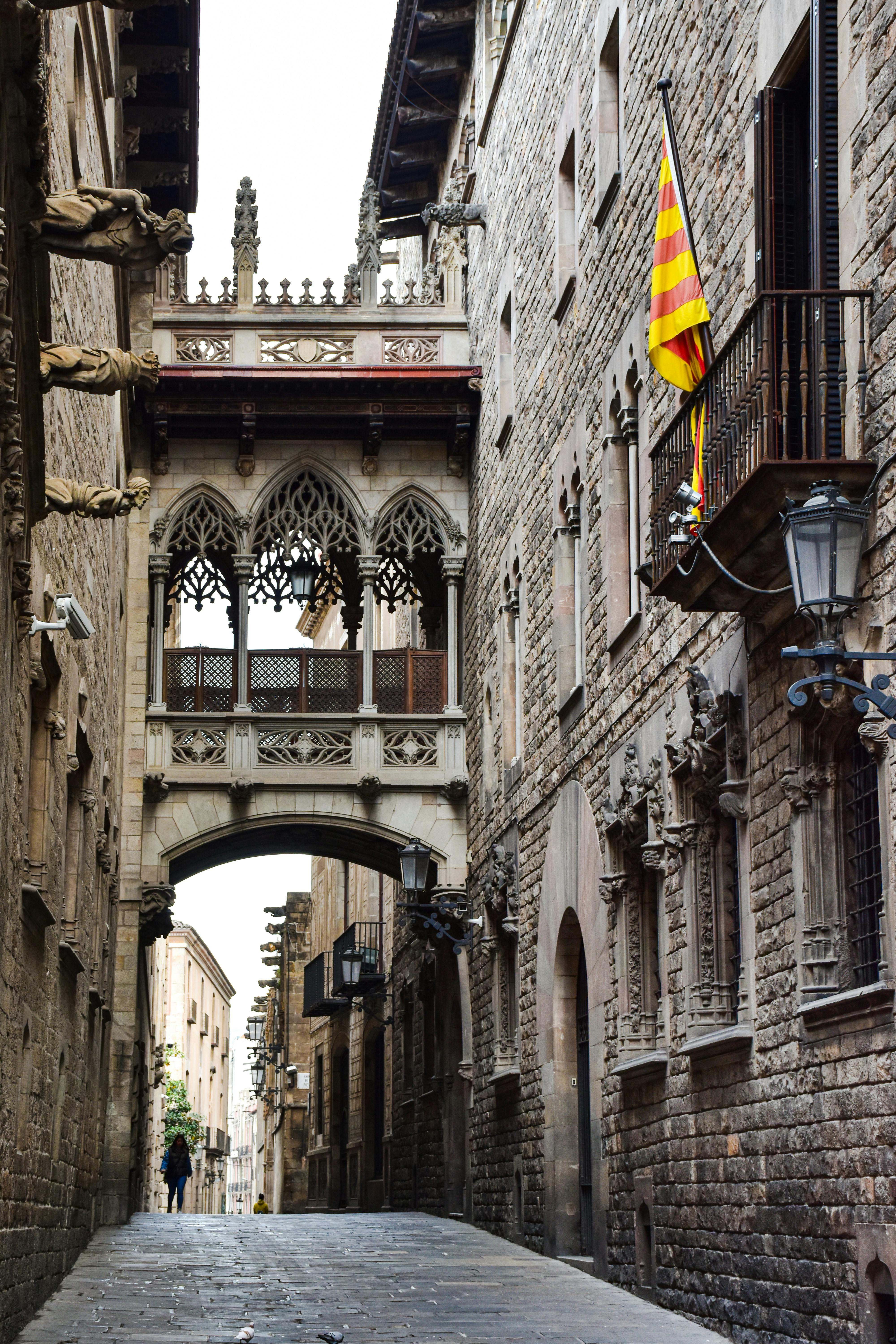 a narrow street with a stone archway and a flag