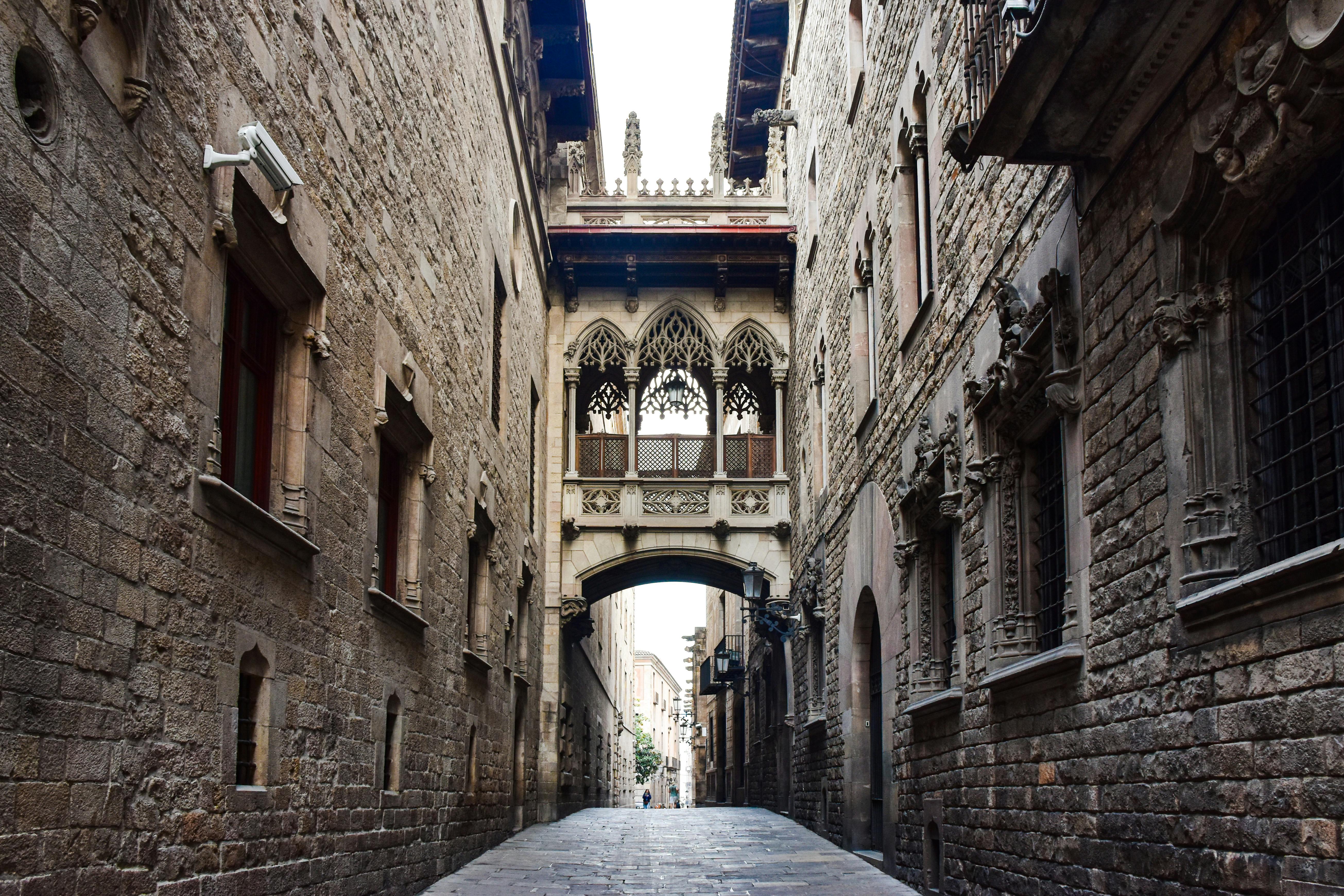 a narrow alley with a stone archway and a clock tower