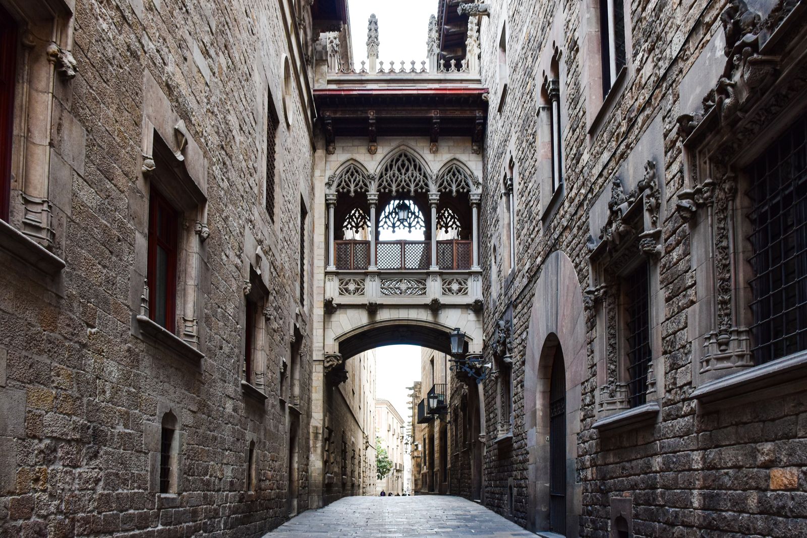 The carved Gothic Pont del Bisbe footbridge arching over a quiet stone lane in Barcelona's Gothic Quarter