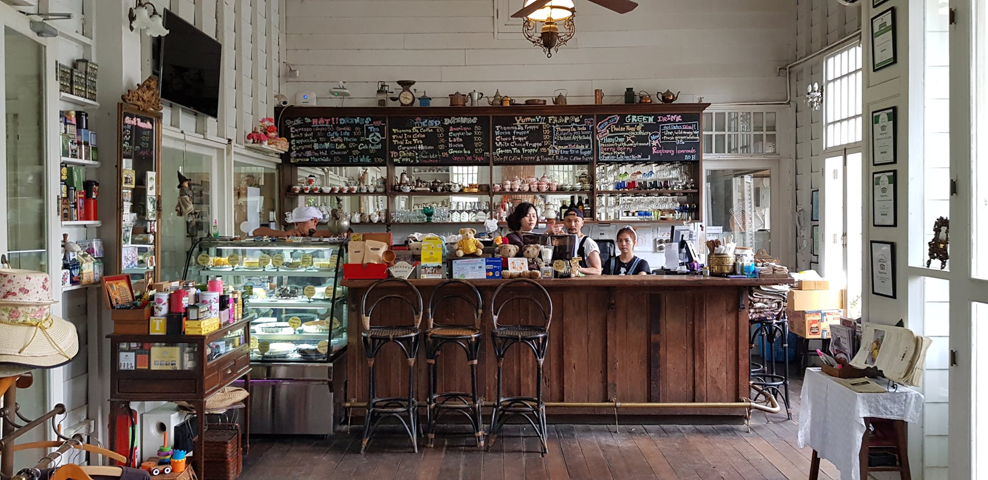 Charming café interior featuring a rustic wooden counter, menu board, and customers enjoying coffee indoors.