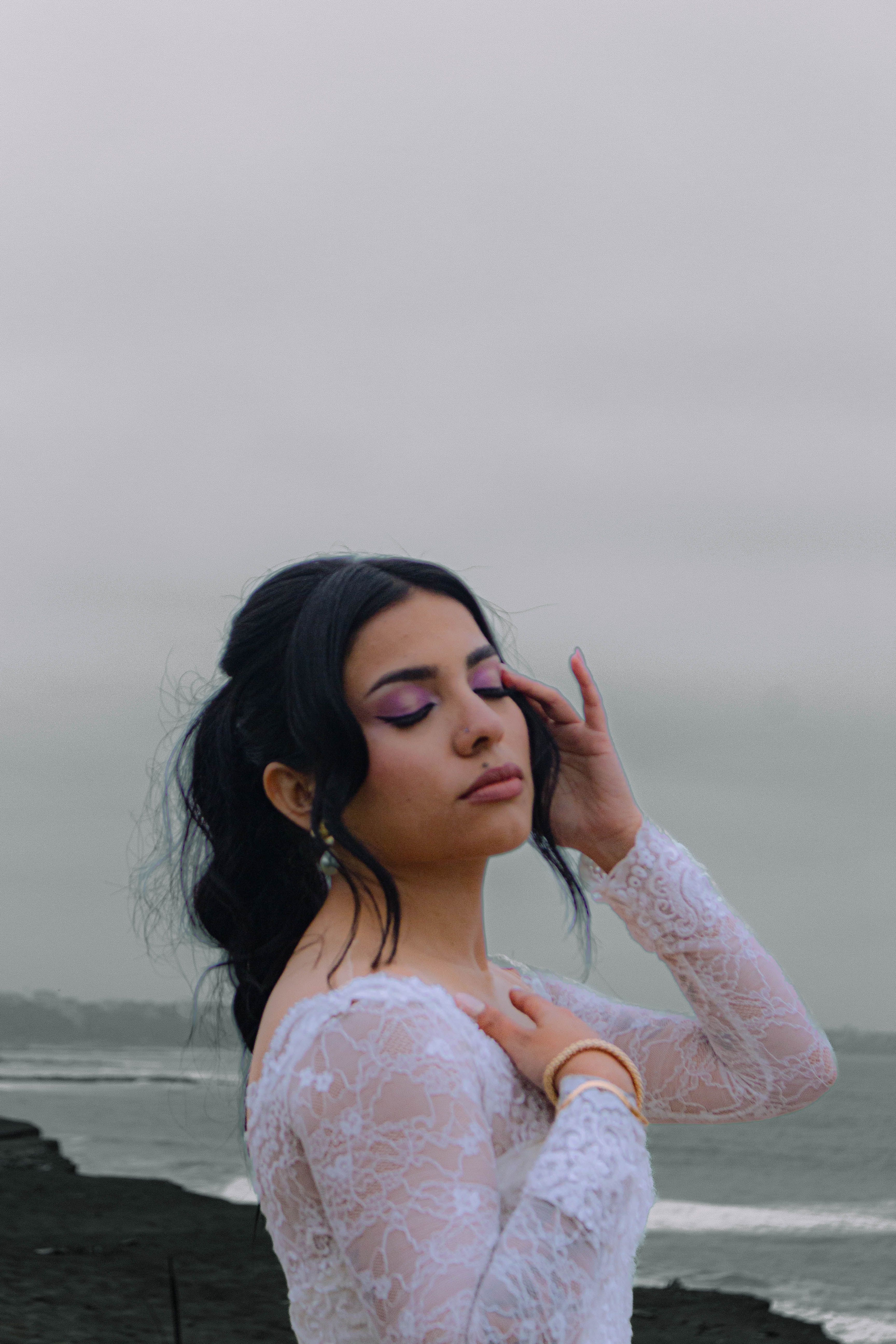 A woman in a wedding dress standing on the beach · Free Stock Photo