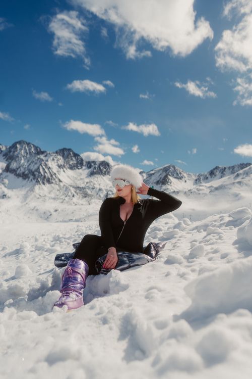 Free Woman sitting in the winter snow of Andorra, enjoying mountain views. Stock Photo